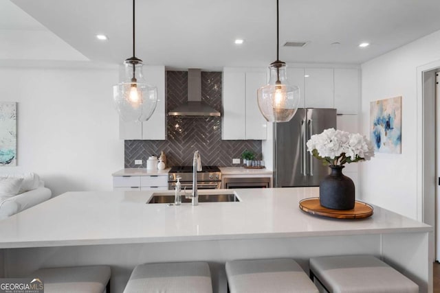 kitchen with decorative light fixtures, wall chimney exhaust hood, decorative backsplash, high end appliances, and white cabinetry