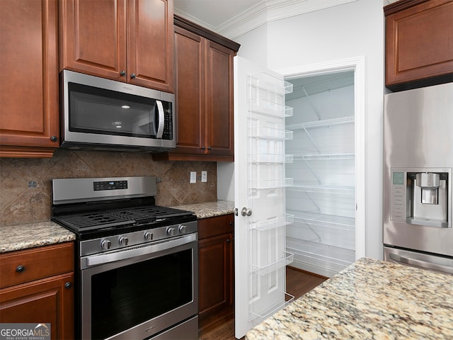 kitchen with light stone countertops, appliances with stainless steel finishes, crown molding, and dark wood-type flooring