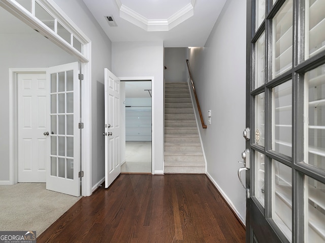 foyer featuring crown molding, dark hardwood / wood-style flooring, and a raised ceiling