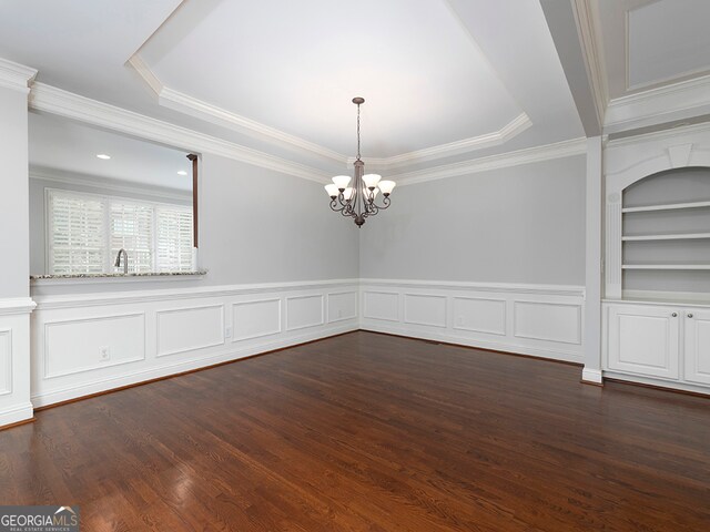 unfurnished dining area with dark wood-type flooring, crown molding, a tray ceiling, an inviting chandelier, and built in features