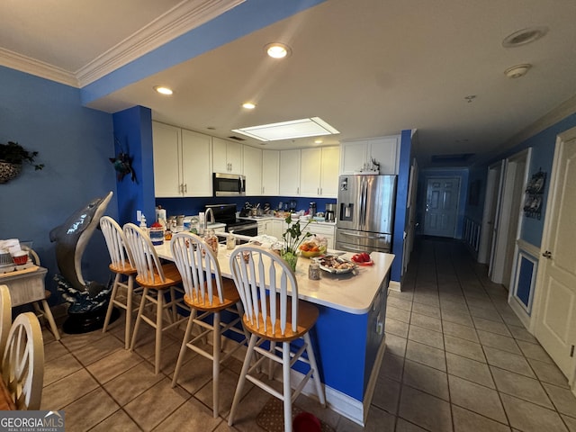 kitchen featuring crown molding, light countertops, appliances with stainless steel finishes, white cabinetry, and a peninsula