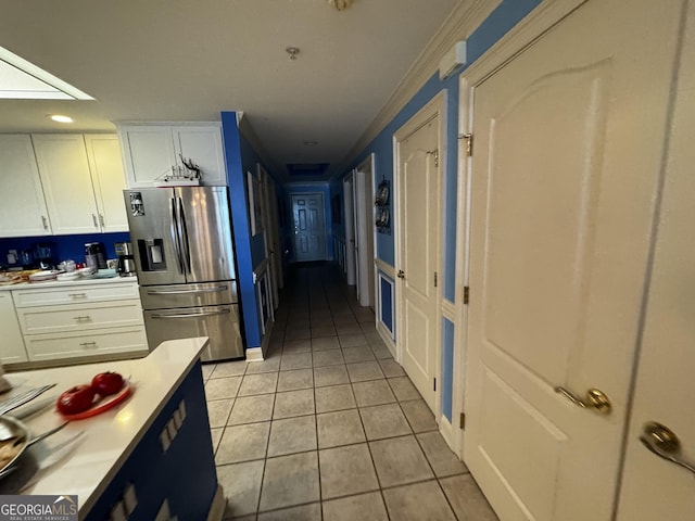 kitchen featuring light countertops, light tile patterned flooring, stainless steel refrigerator with ice dispenser, and white cabinetry