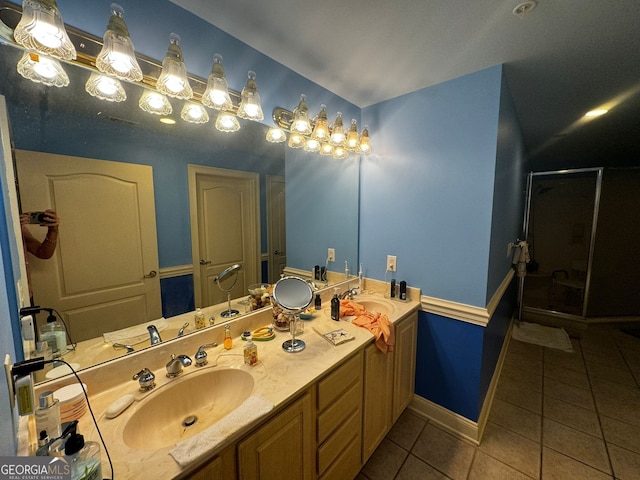 bathroom with double vanity, a shower stall, a sink, and tile patterned floors