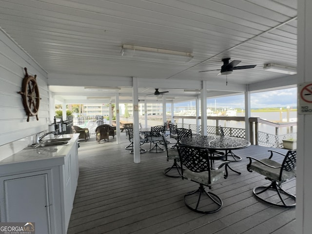 wooden deck featuring ceiling fan, outdoor dining space, and a sink