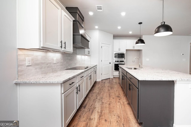 kitchen featuring a center island with sink, decorative light fixtures, ceiling fan, and light stone countertops