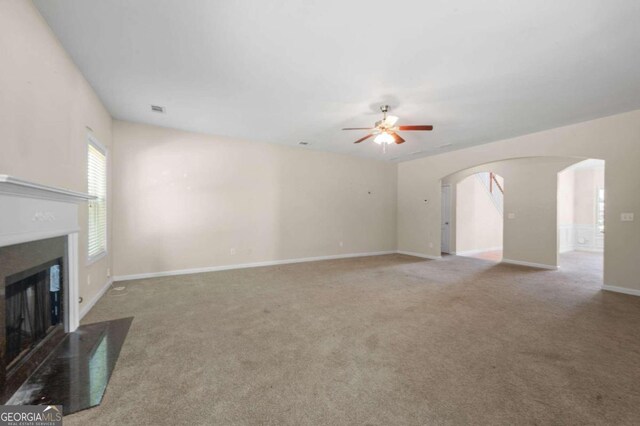 unfurnished living room with ceiling fan and carpet