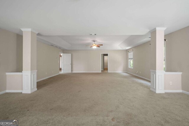 spare room featuring ceiling fan, decorative columns, and light carpet