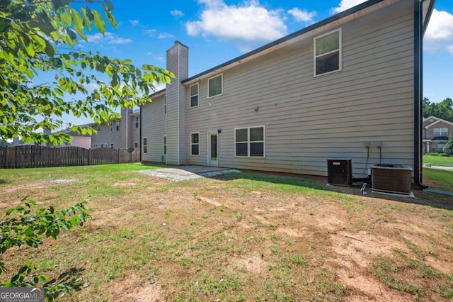 rear view of property with central AC and a yard