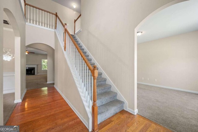 staircase featuring hardwood / wood-style flooring, a high ceiling, and ceiling fan