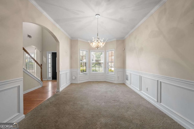 unfurnished dining area featuring a chandelier, ornamental molding, and light colored carpet