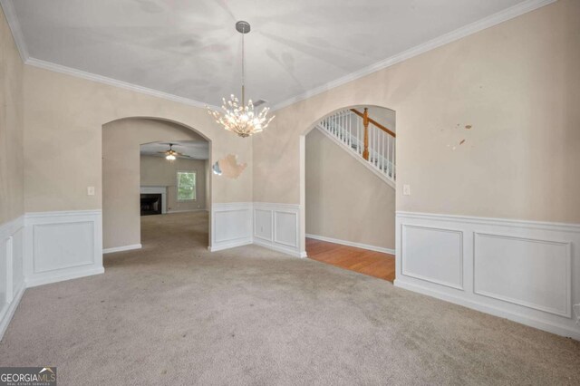 unfurnished room featuring ceiling fan with notable chandelier, ornamental molding, and light carpet