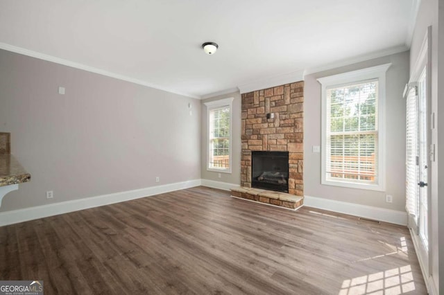 unfurnished living room with hardwood / wood-style flooring, a stone fireplace, plenty of natural light, and crown molding