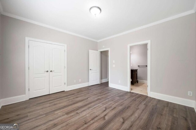 unfurnished bedroom with ornamental molding, ensuite bath, and wood-type flooring