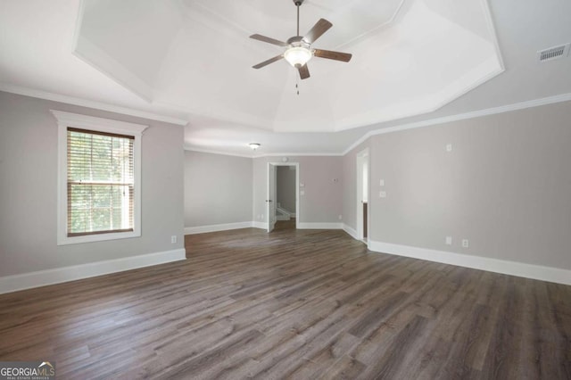 unfurnished room with a raised ceiling, crown molding, and dark wood-type flooring