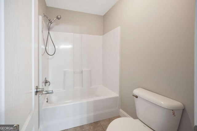 bathroom featuring shower / bathing tub combination, toilet, and tile patterned flooring