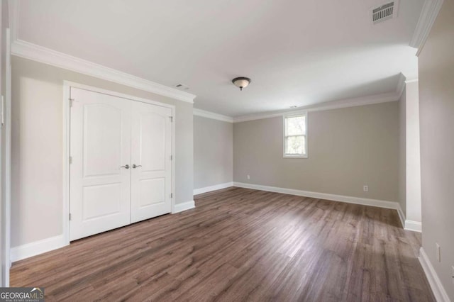 unfurnished bedroom with a closet, crown molding, and dark hardwood / wood-style floors