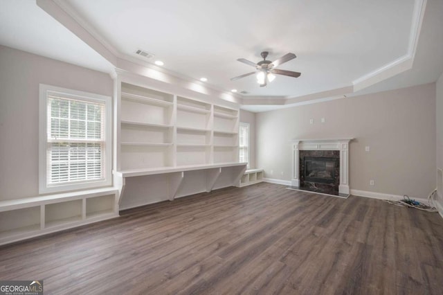 unfurnished living room featuring ceiling fan, a raised ceiling, hardwood / wood-style floors, and a premium fireplace