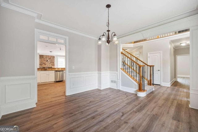 unfurnished dining area featuring hardwood / wood-style flooring, an inviting chandelier, crown molding, and sink