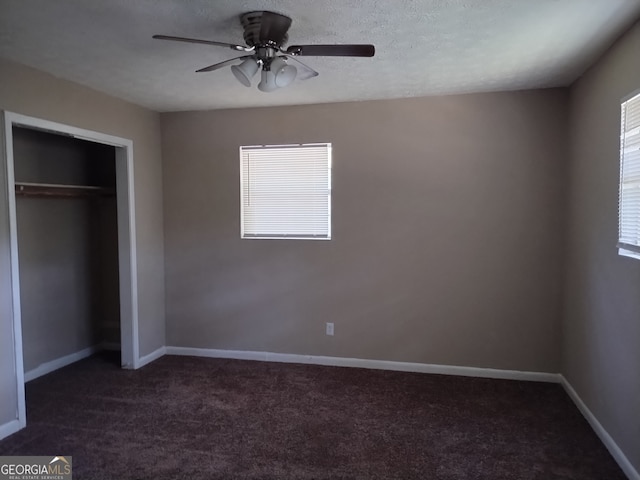 unfurnished bedroom featuring dark carpet, ceiling fan, and a closet