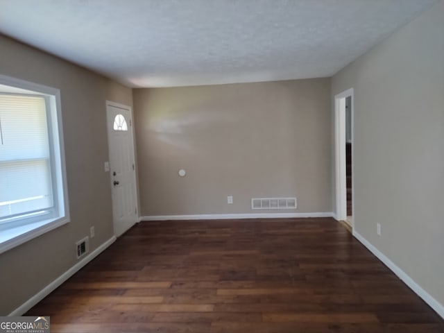 empty room with dark hardwood / wood-style floors and a healthy amount of sunlight