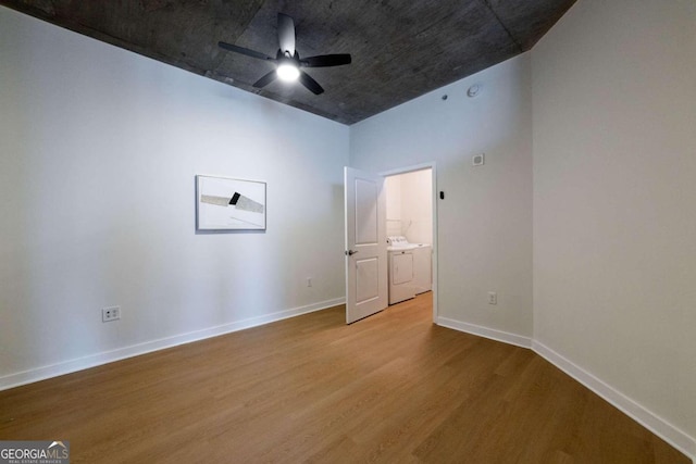 spare room with ceiling fan, washing machine and dryer, and wood-type flooring