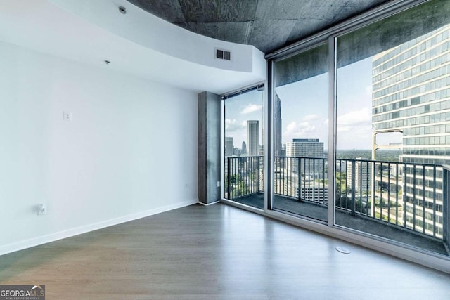 spare room featuring a wall of windows and hardwood / wood-style flooring