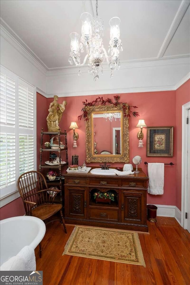 interior space featuring ornamental molding, an inviting chandelier, vanity, and wood-type flooring