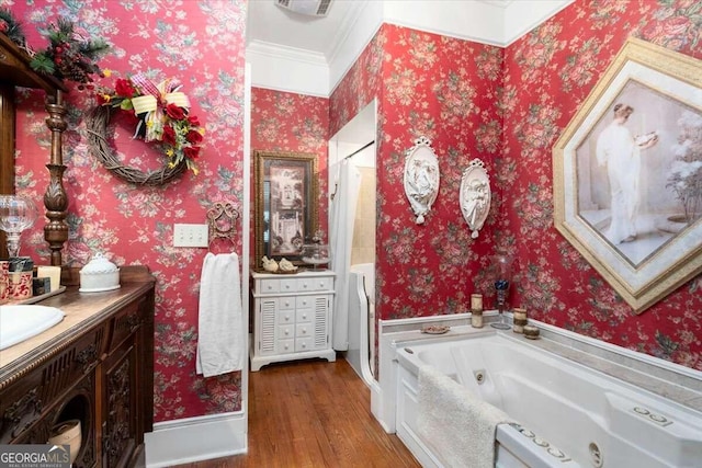 bathroom with hardwood / wood-style floors, a bathtub, ornamental molding, and vanity