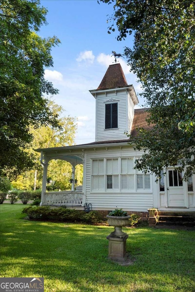 rear view of property featuring a lawn