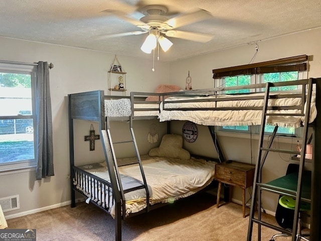 bedroom featuring carpet flooring, ceiling fan, and a textured ceiling