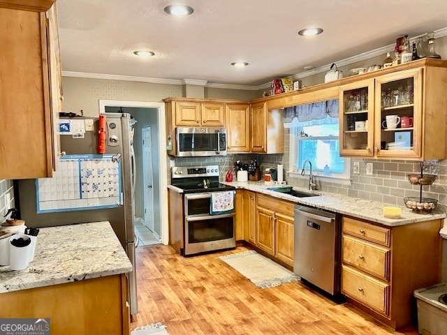 kitchen featuring backsplash, crown molding, light wood-type flooring, stainless steel appliances, and sink