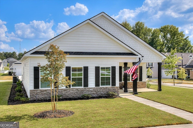 view of front facade featuring stone siding, central AC unit, and a front yard