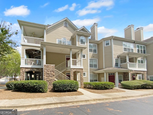 townhome / multi-family property featuring ceiling fan, stone siding, and stairway