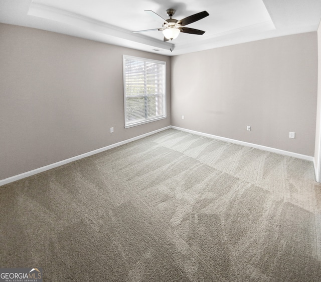 carpeted empty room featuring a raised ceiling and ceiling fan