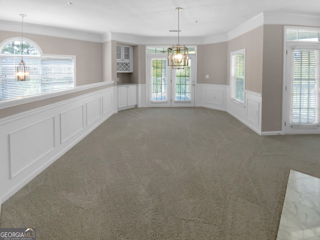 unfurnished dining area featuring ornamental molding, carpet, and a notable chandelier