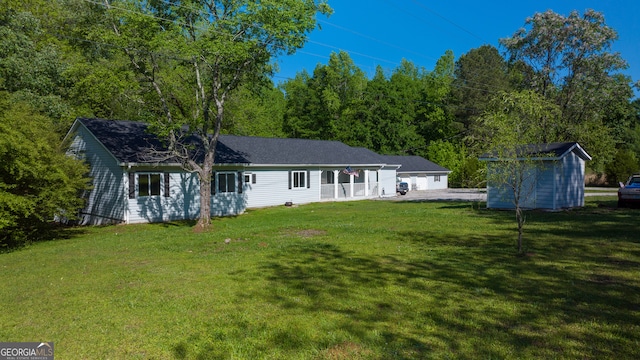 rear view of property featuring a yard and a storage unit