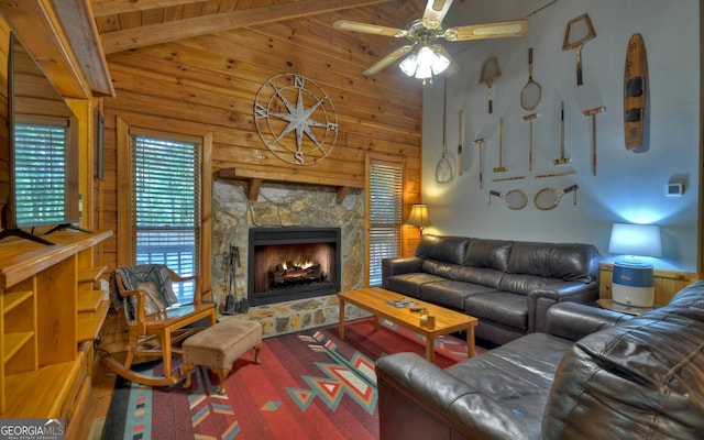 living room with wood walls, a stone fireplace, hardwood / wood-style flooring, ceiling fan, and vaulted ceiling with beams