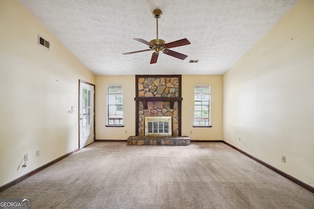 unfurnished living room featuring a textured ceiling, light colored carpet, ceiling fan, and a fireplace