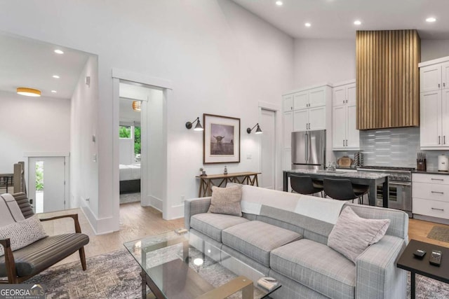 living room with recessed lighting, baseboards, high vaulted ceiling, and light wood finished floors