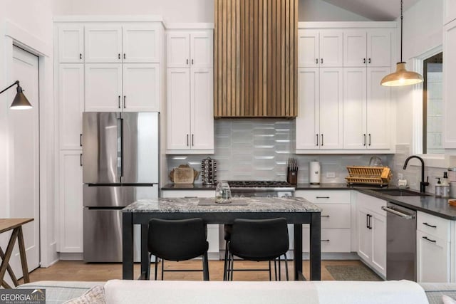 kitchen featuring decorative backsplash, white cabinets, appliances with stainless steel finishes, and a sink