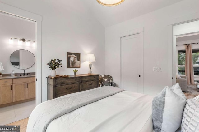 bedroom featuring a sink, connected bathroom, and lofted ceiling