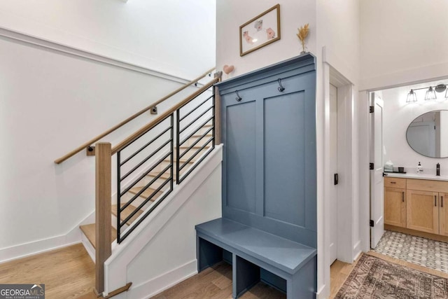 mudroom featuring light wood-style flooring, baseboards, and a sink