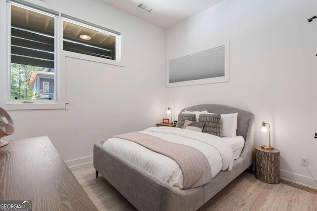 bedroom with visible vents, baseboards, and wood finished floors