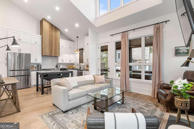 living area with recessed lighting, high vaulted ceiling, and light wood-style floors