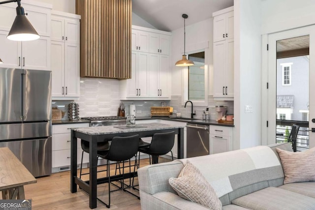 kitchen featuring dark countertops, decorative backsplash, stainless steel appliances, and a sink