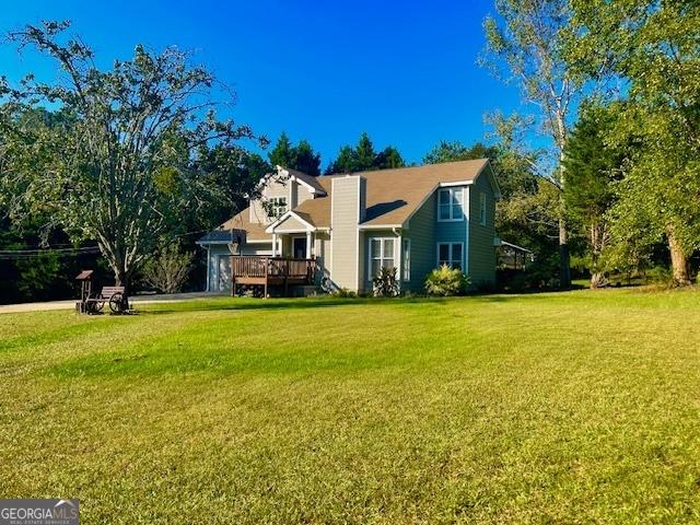 view of front of house featuring a wooden deck, a chimney, and a front lawn