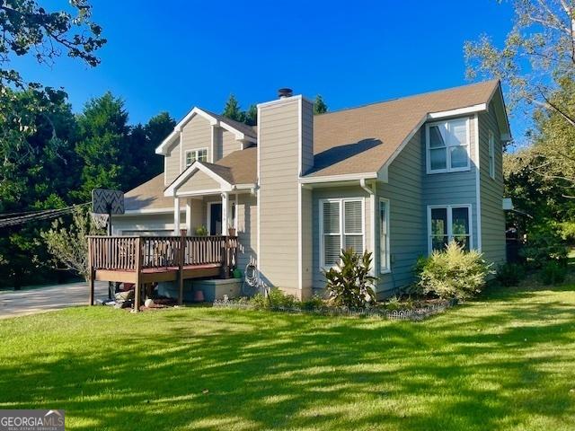 exterior space with a chimney, a deck, and a lawn