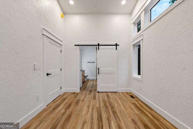 interior space with a barn door, a healthy amount of sunlight, and light wood-type flooring