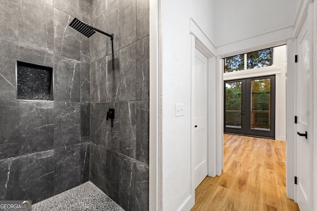 bathroom featuring hardwood / wood-style floors, french doors, and a tile shower