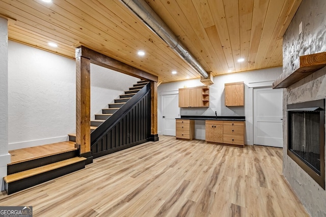 interior space with light wood-type flooring, wood ceiling, and a fireplace